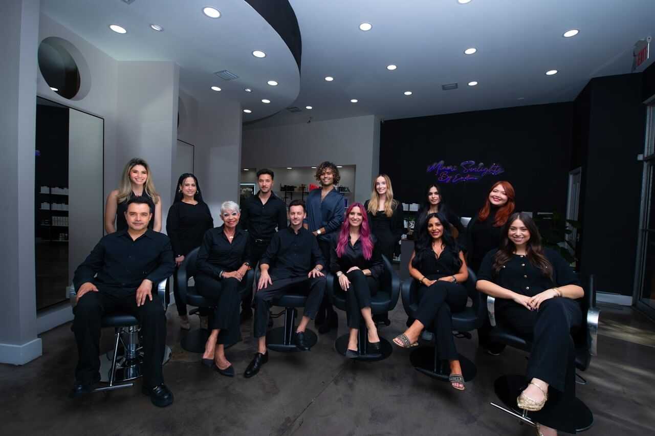 Team of stylists in modern salon, posing together in black outfits.