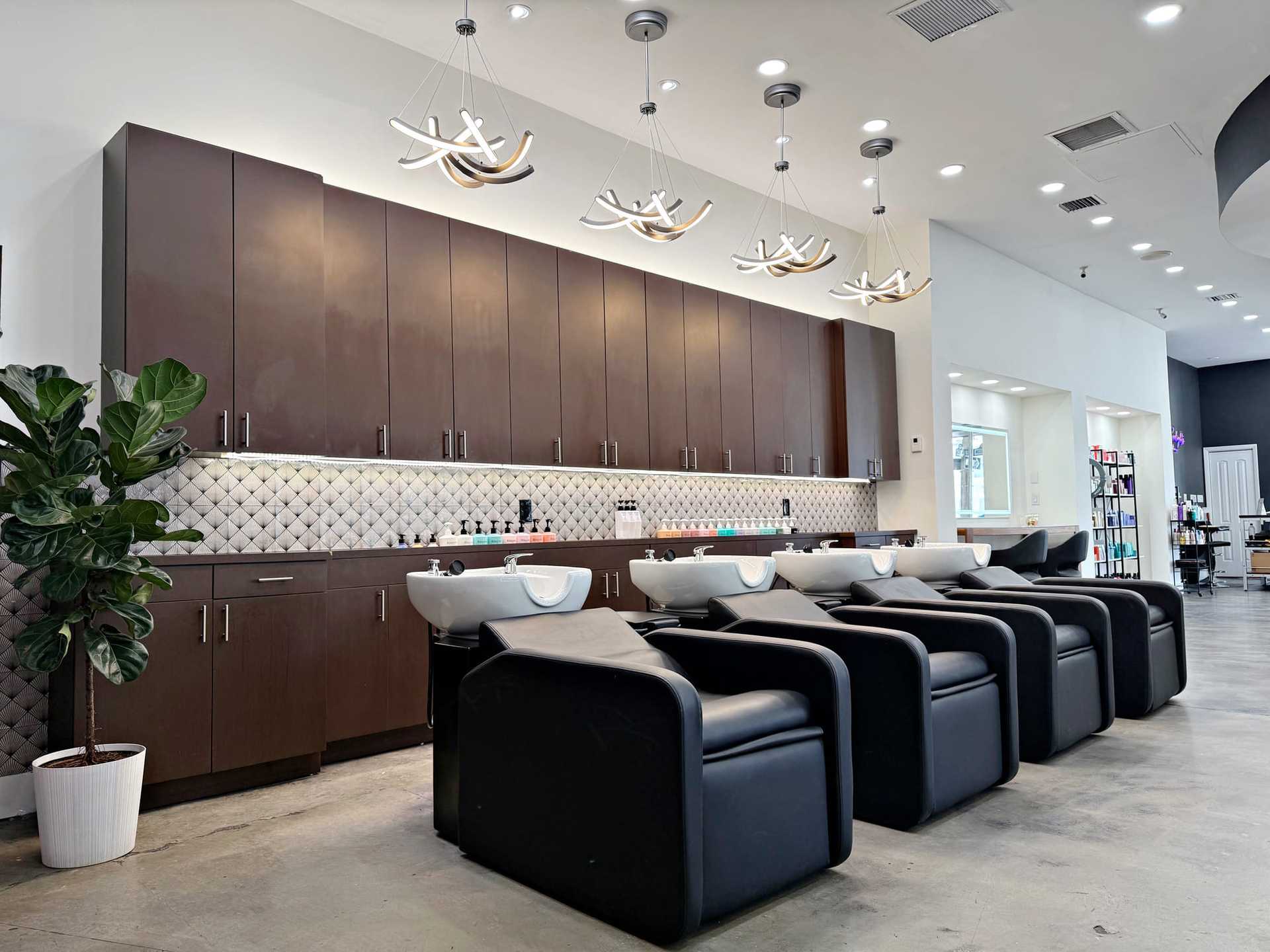 Modern hair salon with washing stations, dark cabinets, and stylish lighting.